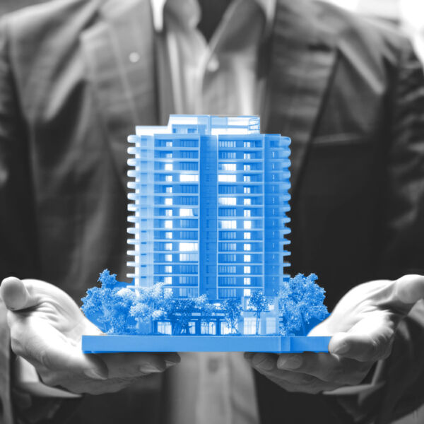 Businessman holding the condo type home house model for advertisement